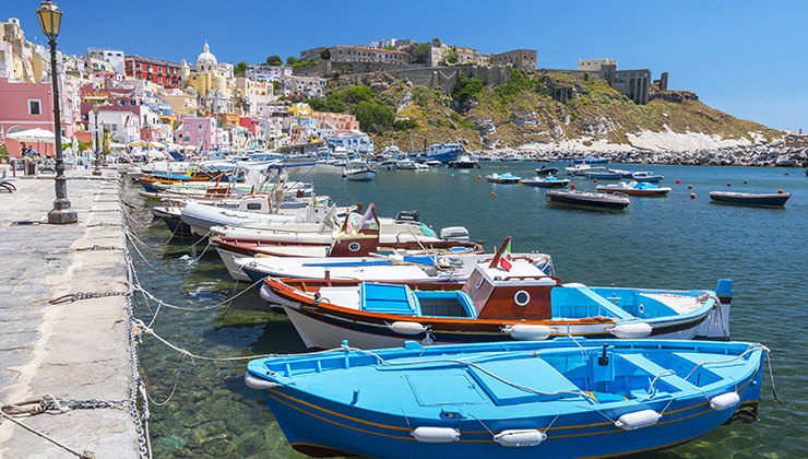The port of Marina Corricella with colorful boats and houses in Terra Murata, Procida Island in Italy.