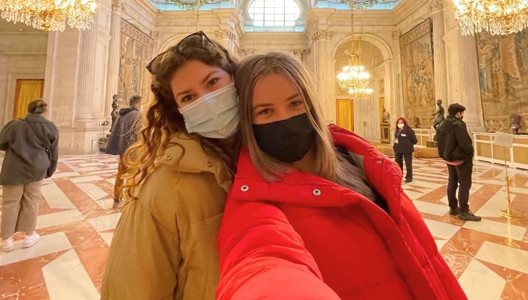 Two students wearing masks take a selfie in the Royal Palace of Madrid.