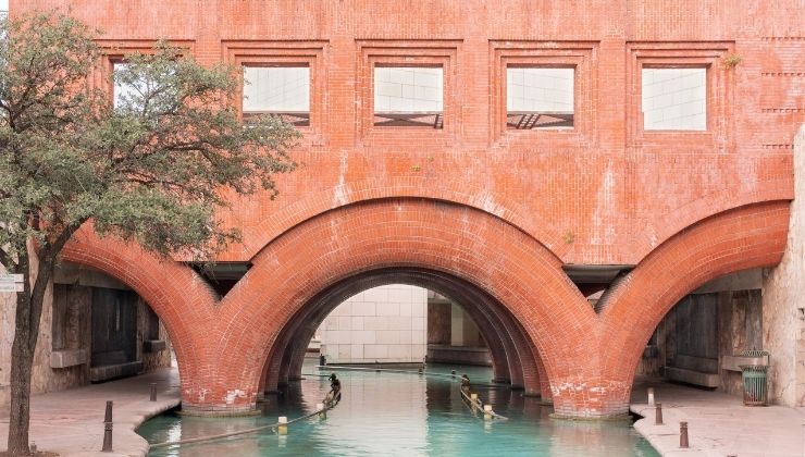 Close up on details of a red brick bridge over water, tree partially in front