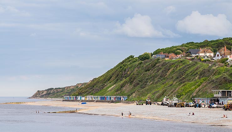 Colorful beach huts lined up on the beach below cliffs at Cromer on the North Norfolk coast.