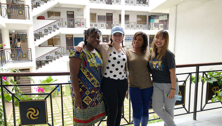 Four friends smile in a building complex in Accra, Ghana.
