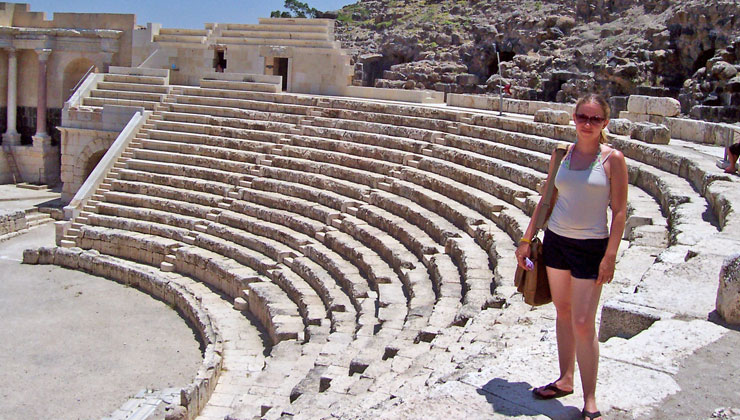 A student standing on the steps of an amphitheater in Israel. 