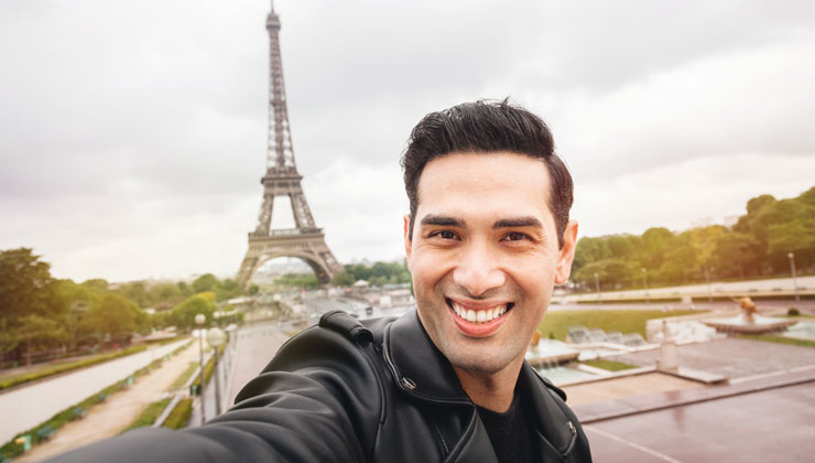 Student smiling in front of the Eiffel Tower in Paris, France.