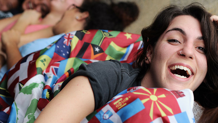Young female student laughs while lying on flag blanket
