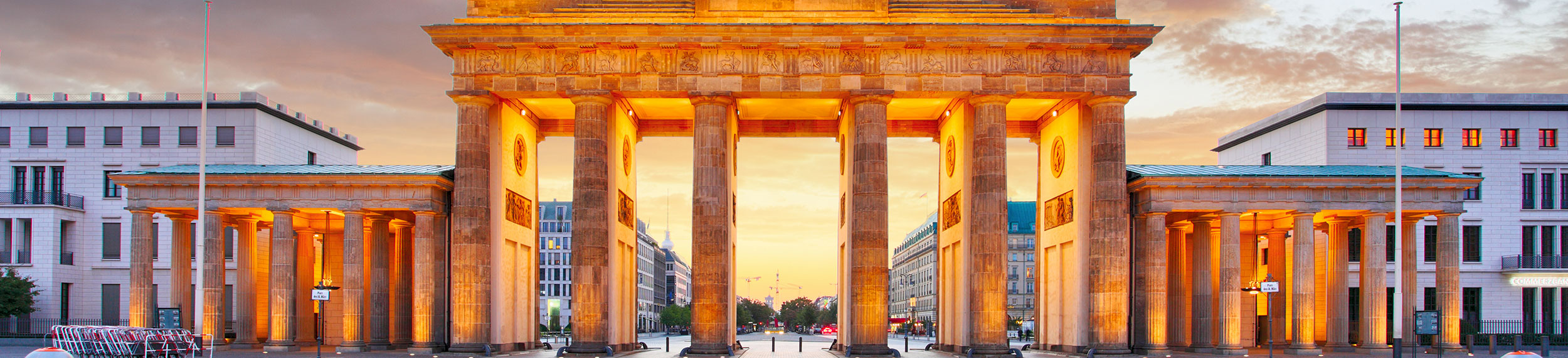 Brandenburg Gate lit up with an orange glow at dusk in Berlin, Germany.