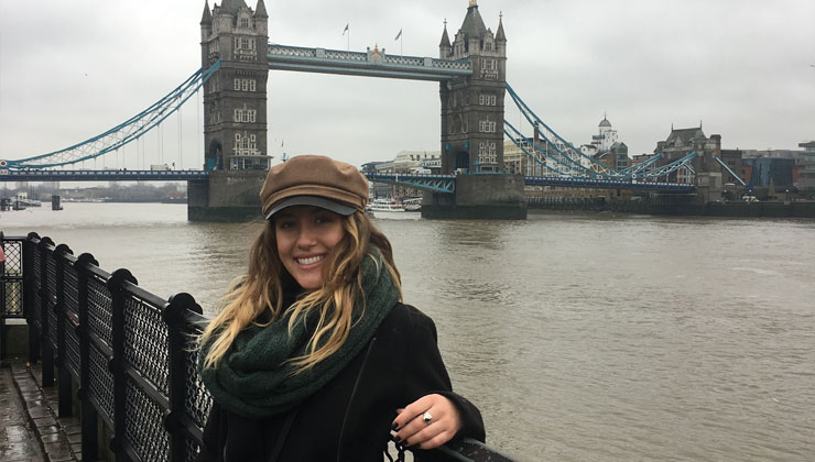 A female student smiling in front of Tower Bridge in London, England. 