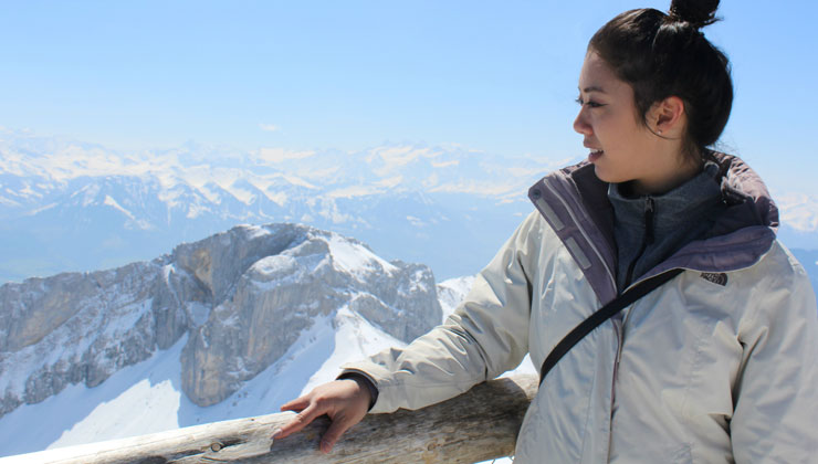 Woman looking over a balcony with a view of the Swiss Alps in Switzerland.