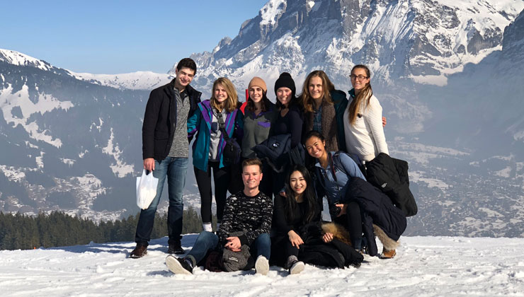 A group shot of students on a mountain with a view of the Swiss Alps in the background in Switzerland. 