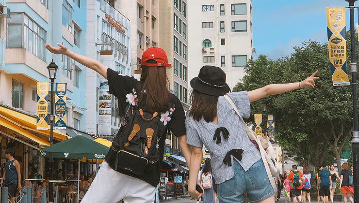 Two friends holding hands and having fun on a sightseeing tour of Hong Kong.