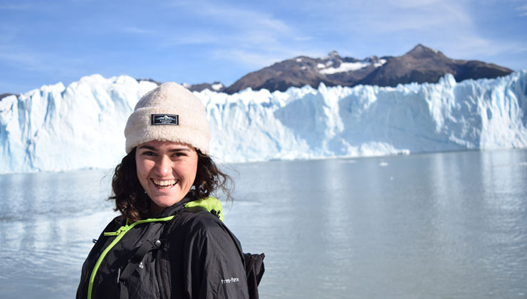 Brenna Cancilla of UC Berkeley smiles in front of an almost frozen lake and glacier at Glaciar Perito Moreno in Argentina.