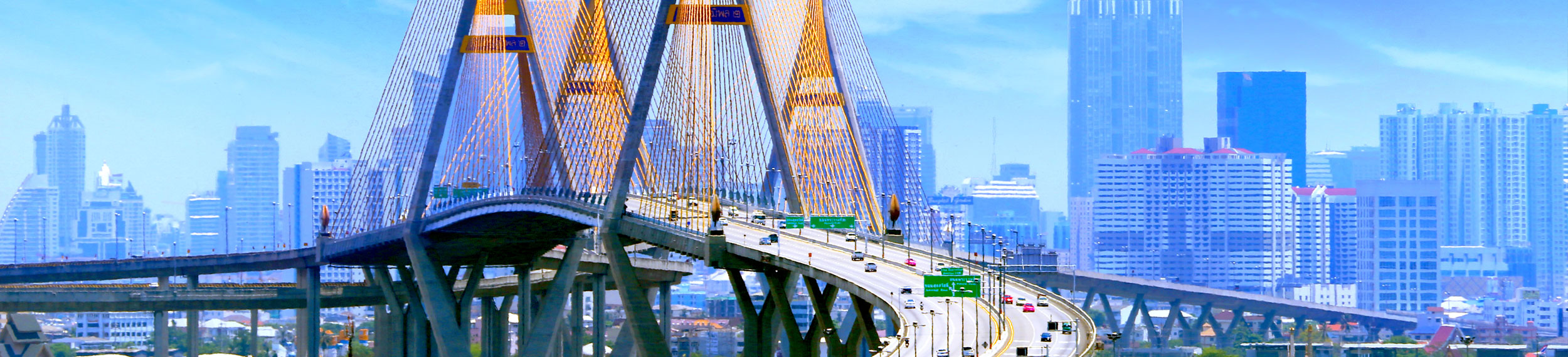 international-Bhumibol Bridge with traffic and blue buildings in the background in Bangkok, Thailand.