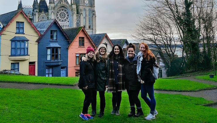UC Los Angleles student with friends smiling for the camera with colorful buildings in the background, Cobh, Ireland.