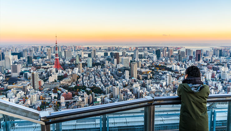 Tourists enjoy the view of Tokyo Tower and skyline from Roppongi Hills in Tokyo, Japan.