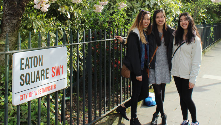 Three students standing next to an Eaton Square sign in London, England. 