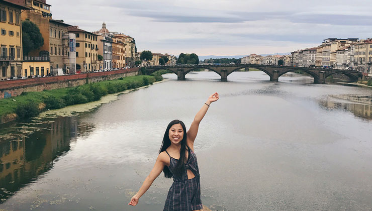 UC Davis student strikes a pose in front of a waterway in Florence, Italy.