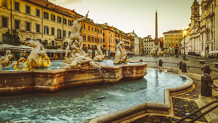 A side view of Piazza Navona, a running fountain with statues on top in Rome, Italy.