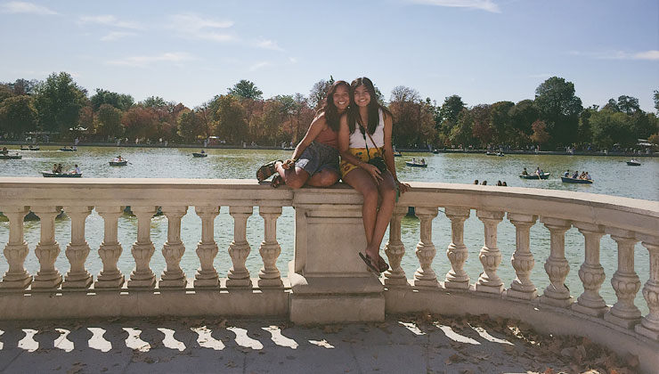Two students sitting on a railing at a park in Madrid, Spain.