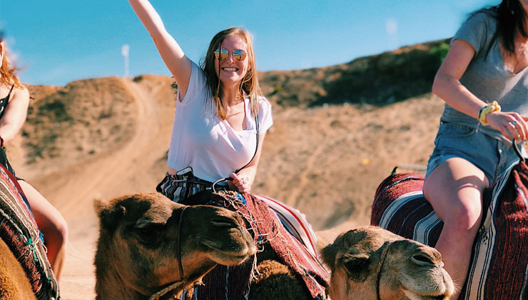 Student smiling at camera riding a camel in Jordan