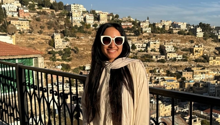 Person wearing sunglasses posing against a balcony with the cityscape in the background