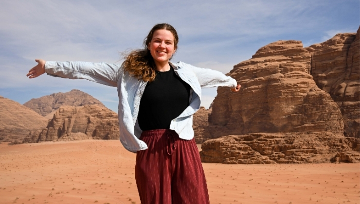 Person with arms open smiling in a red desert with rocks in the background