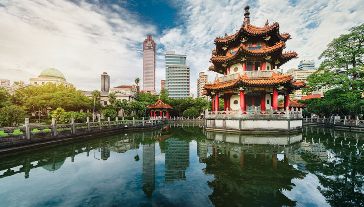 Landscape shot of the traditional architectural building with a reflection in the pond and a view of the Taipei Taiwan skyline. 