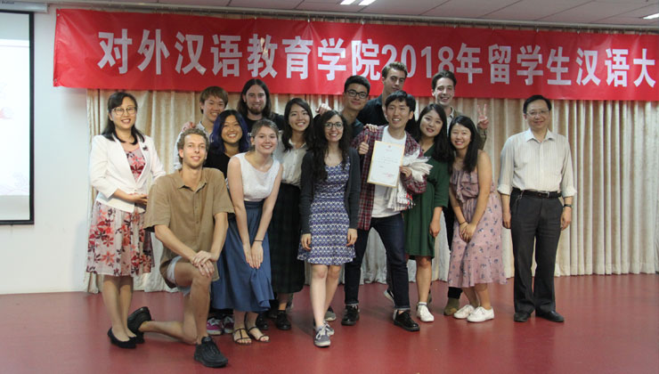 A group shot of students smiling with one student holding up an award after winning a competition in Beijing, China. 