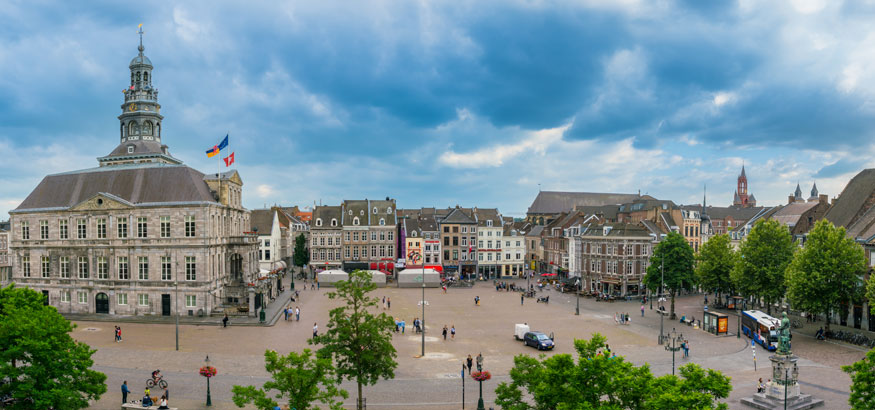 Tourist and locals wander around on the historic Market Square with the Town Hall in the center of town in Maastricht, Netherlands