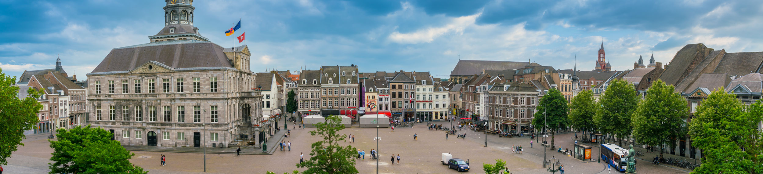 Tourist and locals wander around on the historic Market Square with the Town Hall in the center of town in Maastricht, Netherlands