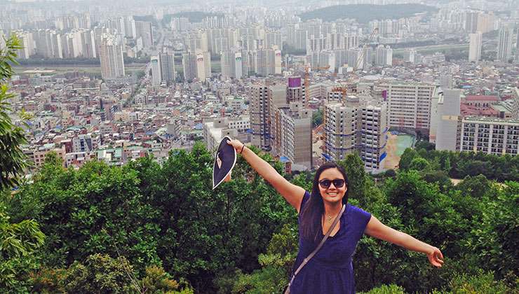 Julia Chung of UC Santa Barbara spreads out her arms with Seoul, Korea, in the background.