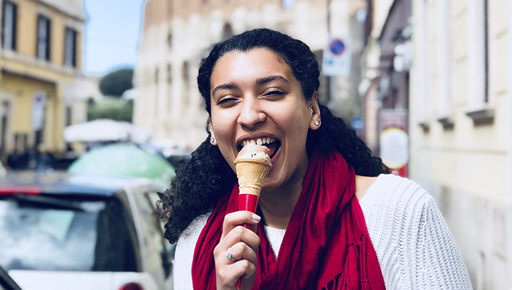 A student smiles and eats ice cream on the streets of Rome, Italy.