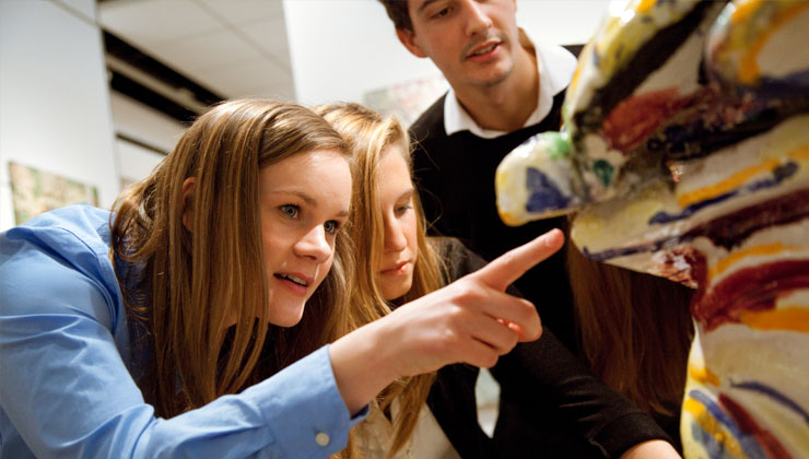 Three students looking at a sculpture. 