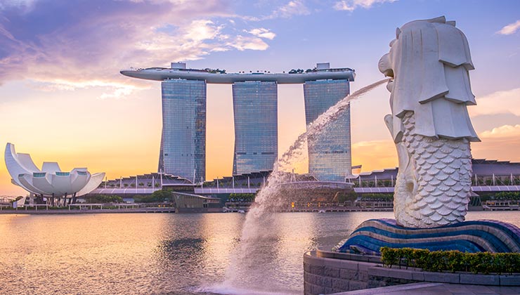 With the head of a lion and body of a fish, the Merlion fountain spouts water into Marina Bay at sunset in Singapore.
