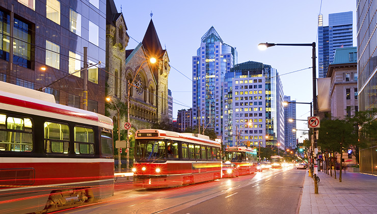 Three bright red street cars go down King Street in Toronto, Ontario, Canada.