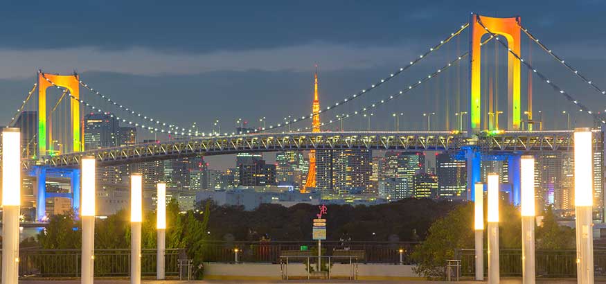 Colorfully lit Rainbow bridge and Tokyo Tower view at sunset from Odaiba, Tokyo.