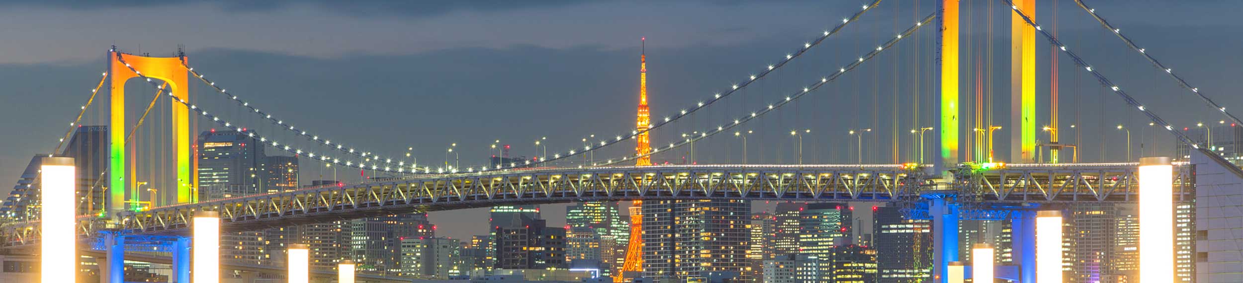 Colorfully lit Rainbow bridge and Tokyo Tower view at sunset from Odaiba, Tokyo.
