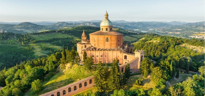 Aerial view of a sunrise-lit chapel a grass-covered valley in the background