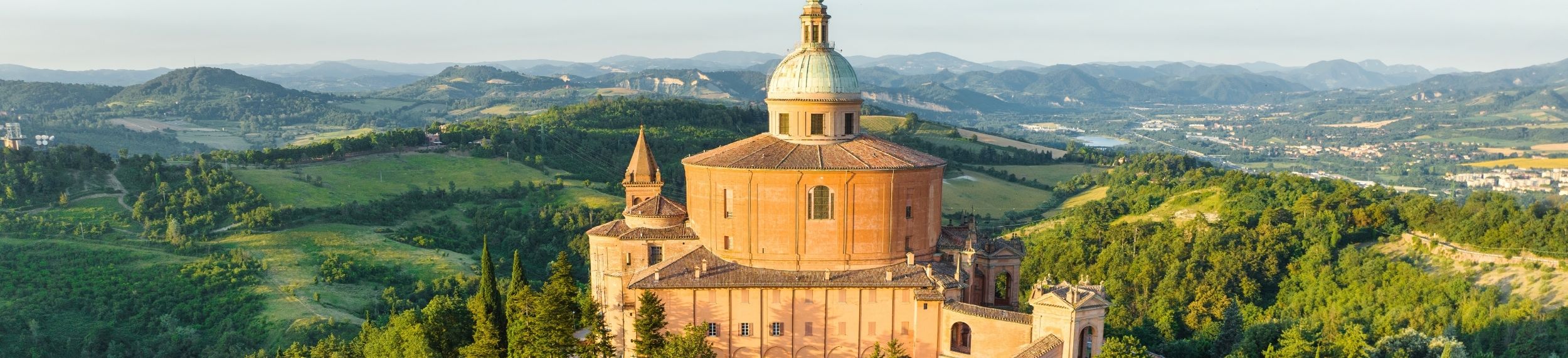 Aerial view of a sunrise-lit chapel a grass-covered valley in the background