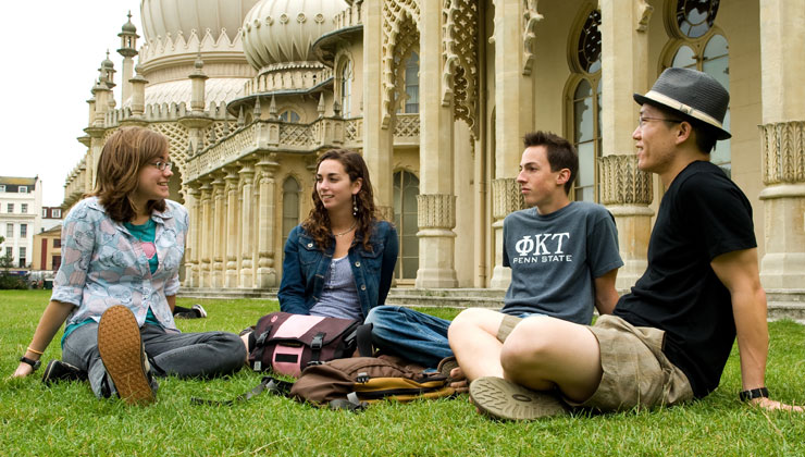 Four students sitting on a grass lawn in Brighton England. 