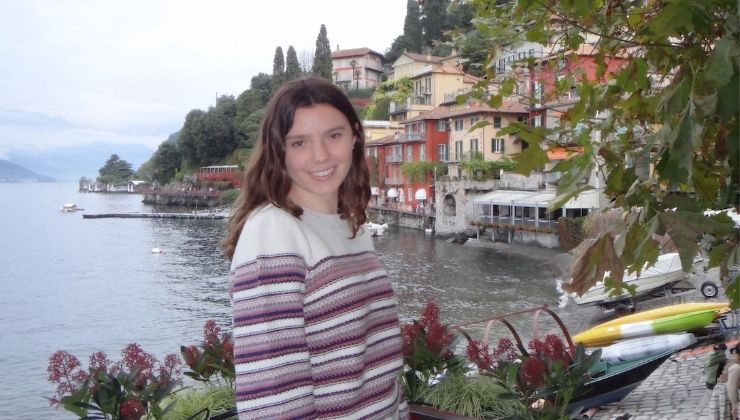 Student poses in front of flowers and Spanish architecture on a hillside and body of water in Barcelona, Spain. 