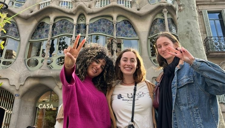 Three students pose for camera in front of ornate apartment building by Gaudi, Barcelona, Spain.