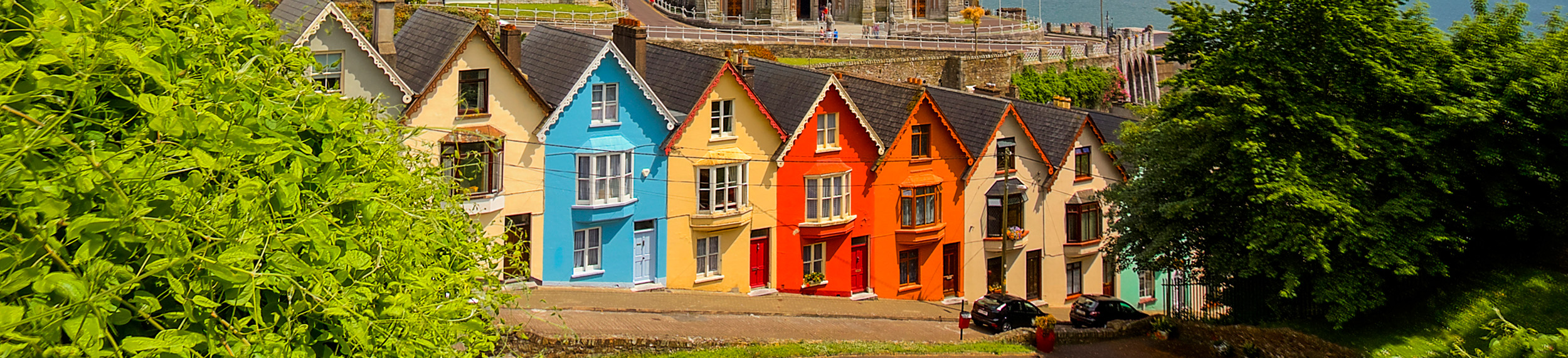 A row of colorful houses in front of St. Colman's Cathedral in Cobh, County Cork, Ireland. 