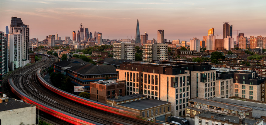 A view of the London trains and skyline at sunset.