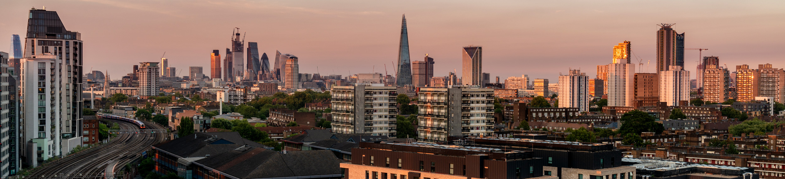 A view of the London trains and skyline at sunset.