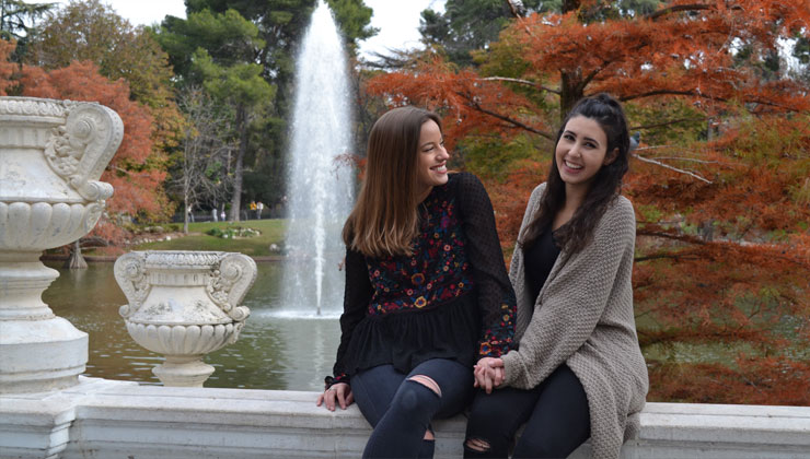 Two smiling students sitting at a fountains in Barcelona, Spain.