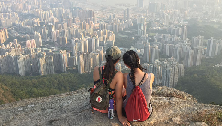 Two students lean on each other while enjoying the view of Hong Kong from Lion Rock.
