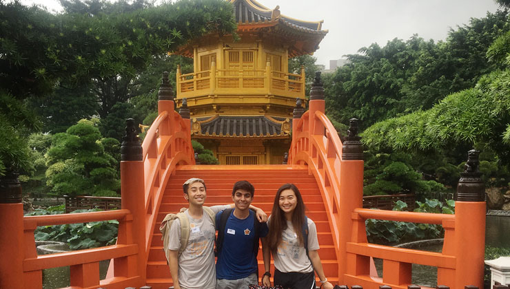 Three students near an orange bridge leading to the The Golden Pavilion of absolute perfection in Nan Lian Garden in Chi Lin Nunnery in Hong Kong