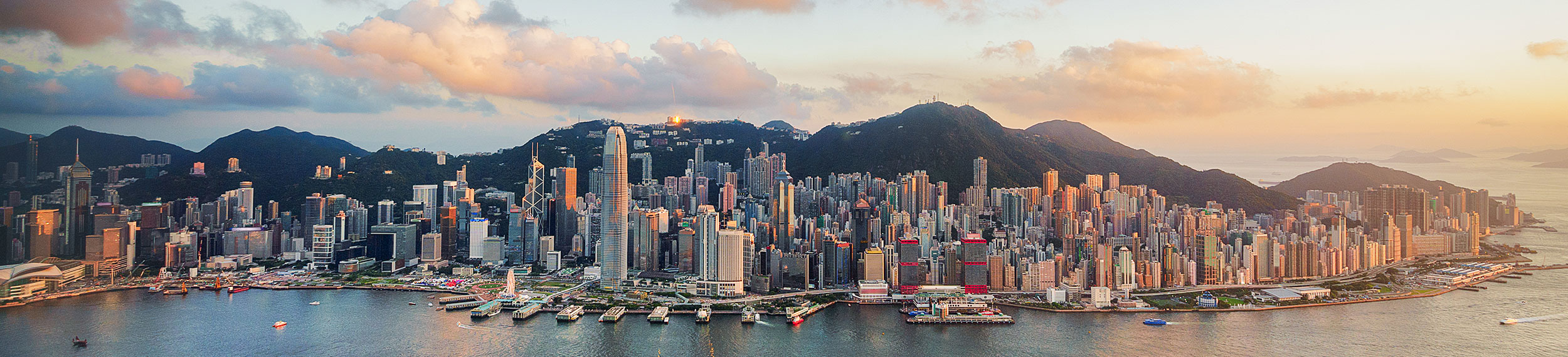 Aerial shot of Victoria Harbor and Hong Kong skyline at sunset. 