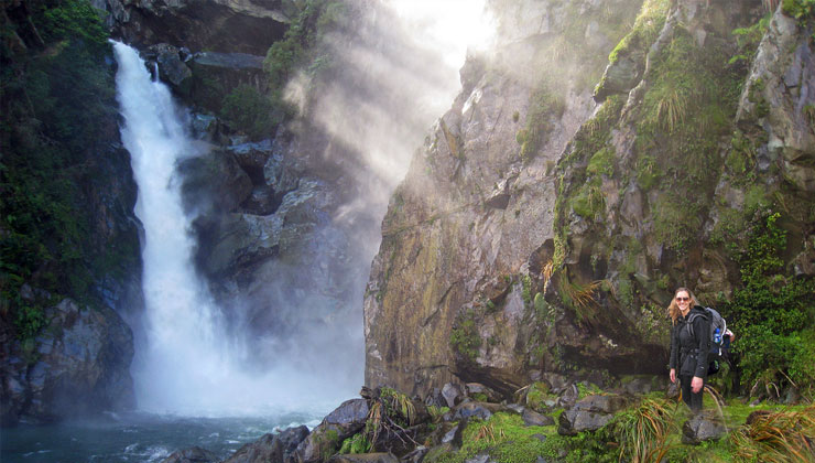 UCEAP student standing next to a waterfall in New Zealand. 