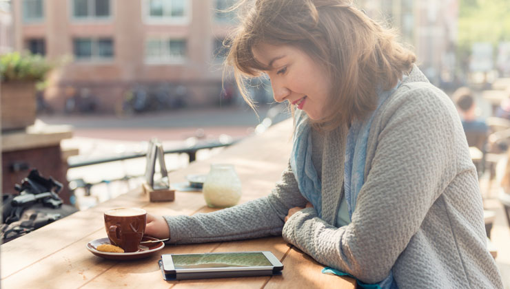 Young woman sitting a cafe and looking at an iPad in the Netherlands. 