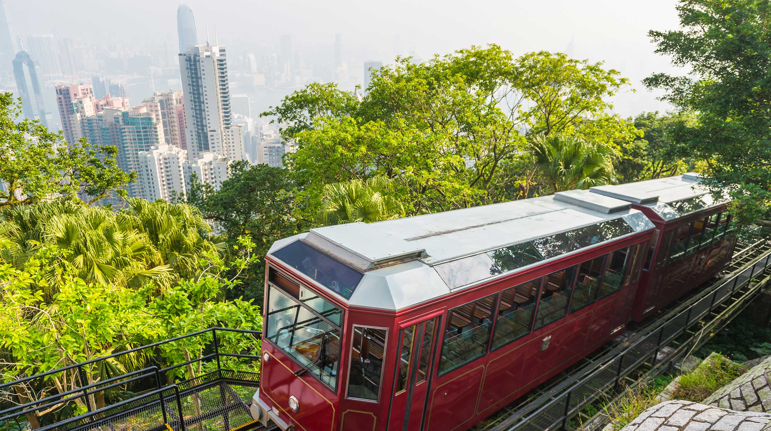 Hong Kong historic red tram climbs Victoria Peak passing skyscrapers in the background